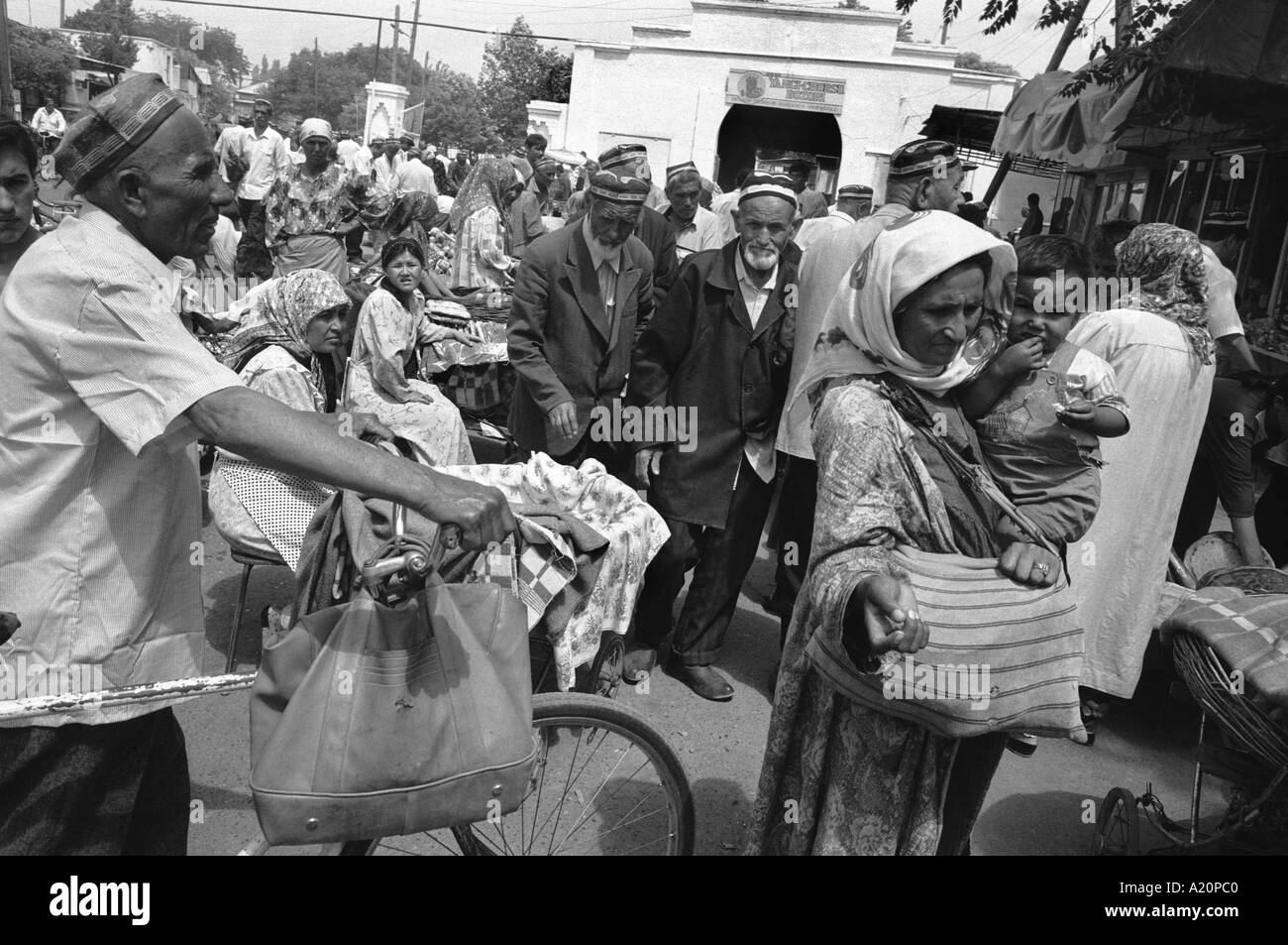 Une femme avec un enfant nous amène de l'argent sur le marché à l'extérieur de la mosquée Juma après la prière du vendredi, Kokand, Ouzbékistan Banque D'Images