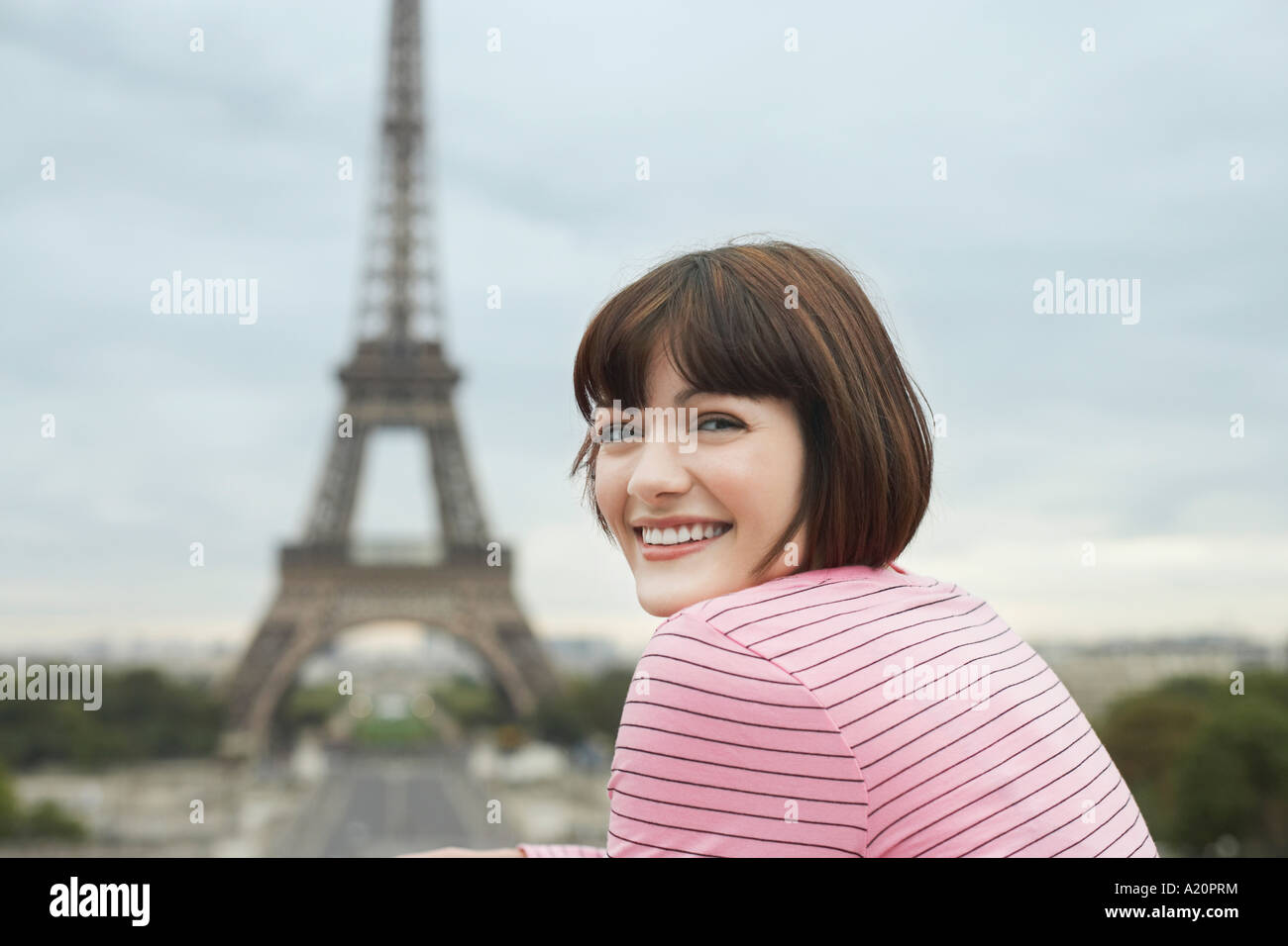 France, Paris, young woman smiling avec Eiffel Tower à distance Banque D'Images