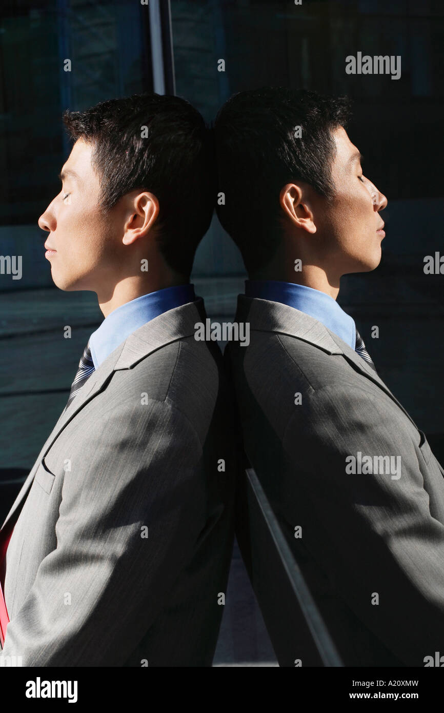 Businessman Leaning Against Wall réfléchissante à l'extérieur, profil Banque D'Images