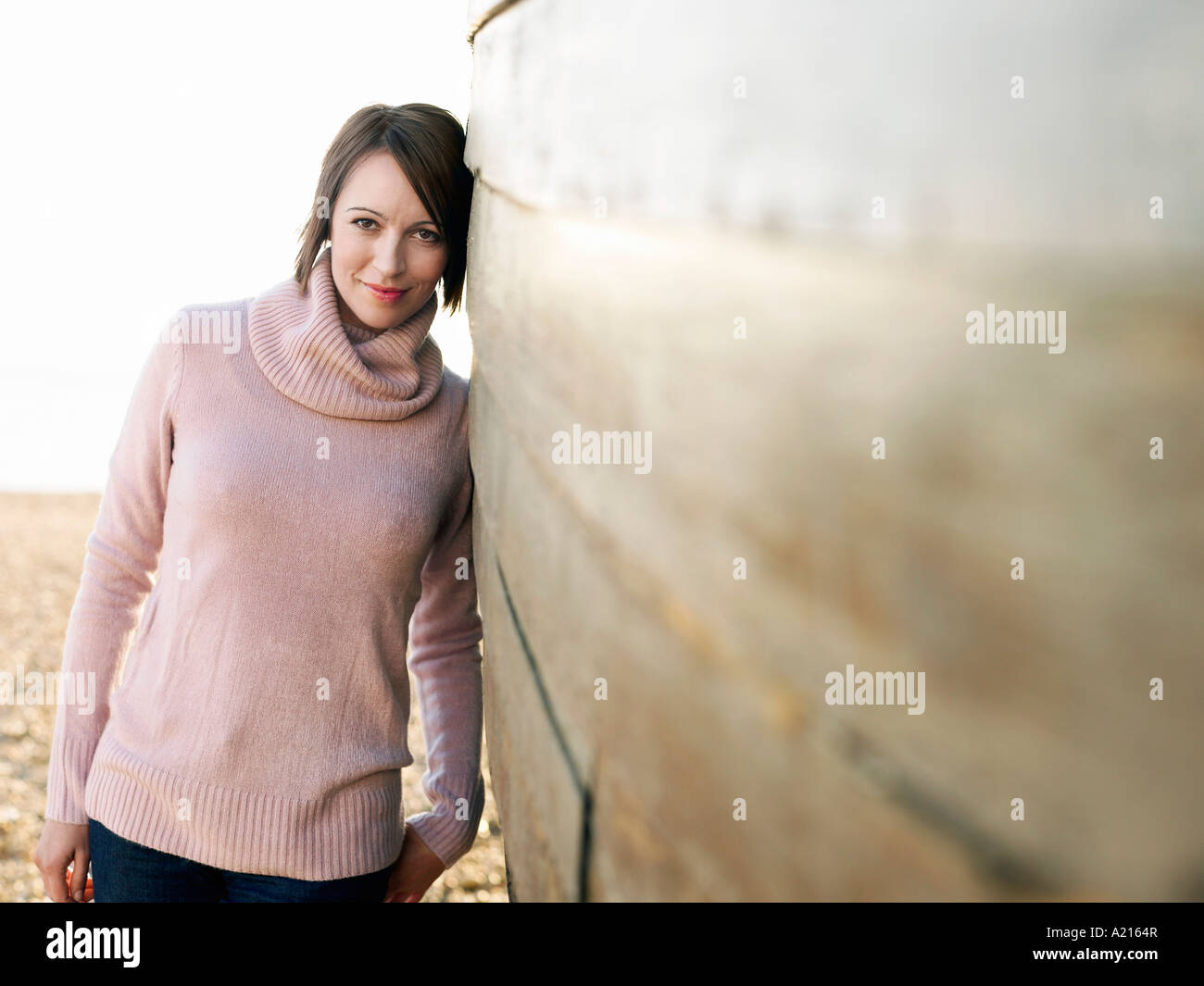 Woman leaning against coque en bois, sur la plage, portrait Banque D'Images