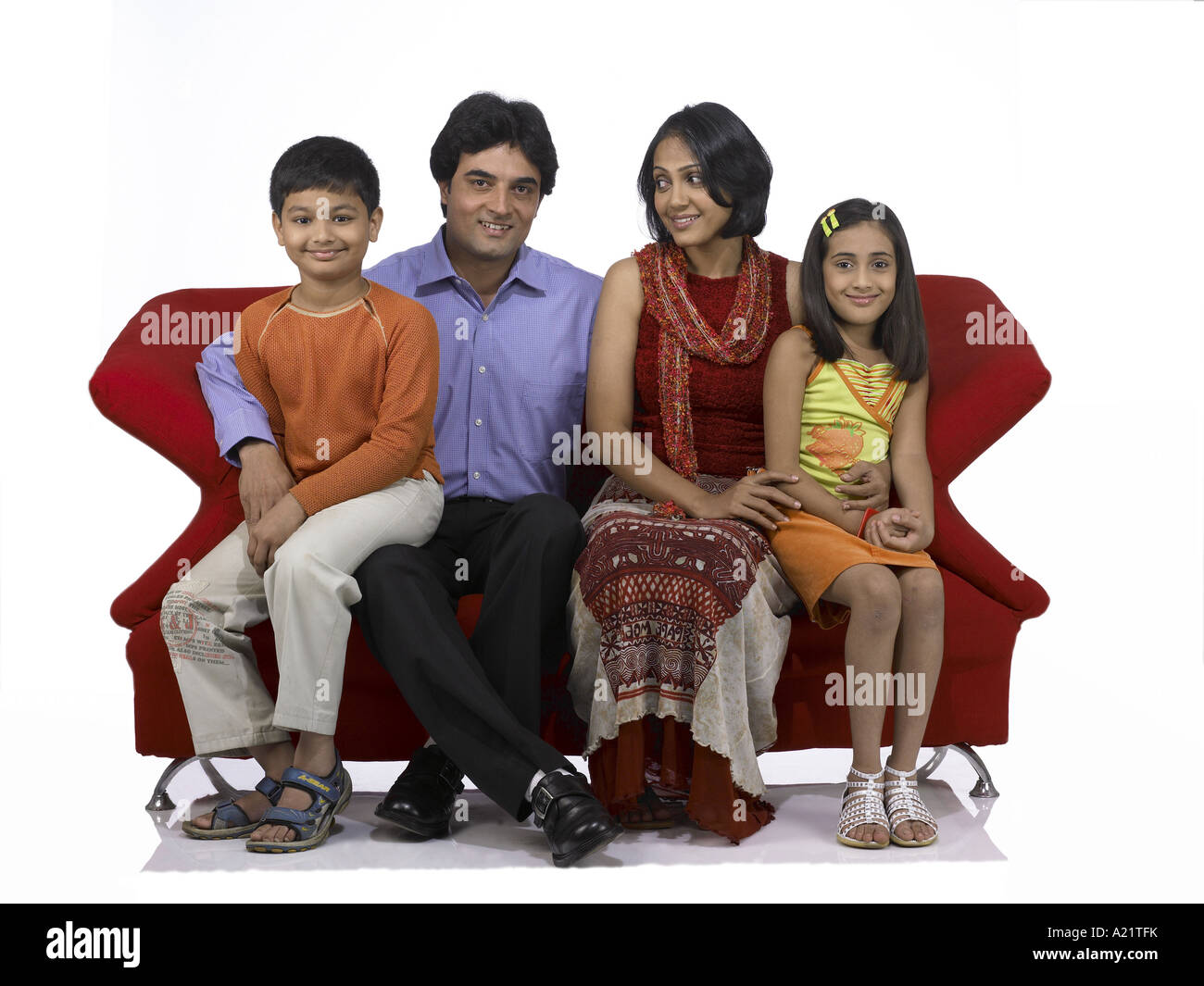 Les Indiens de l'Asie du Sud avec la famille Père Mère fils et fille sitting on sofa smiling Banque D'Images