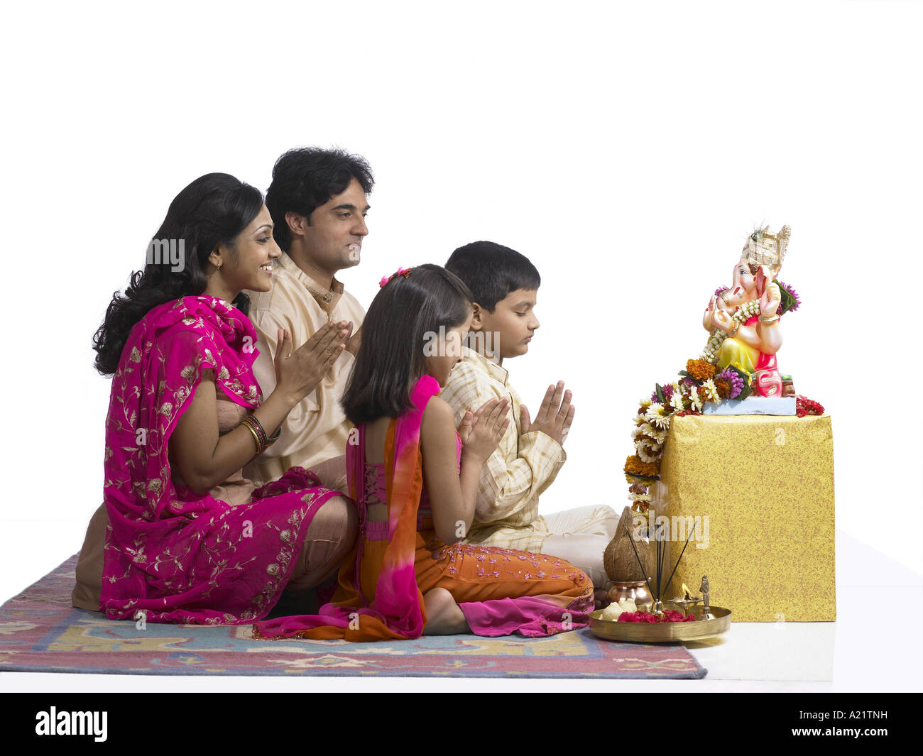 Les Indiens de l'Asie du Sud avec la famille Père Mère Fils Fille assis et priant à Seigneur Ganesha portant un costume traditionnel kurta Banque D'Images