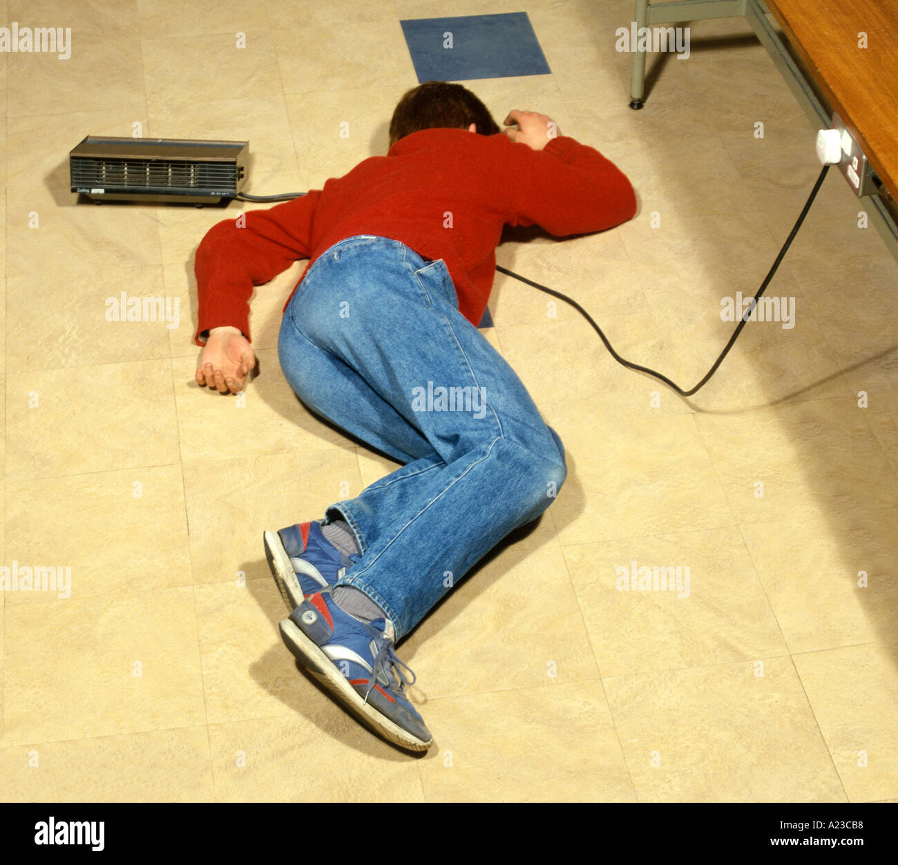 Un adolescent allongé dans votre câble électrique connecté à un radiateur électrique l'électricité peut être dangereux Banque D'Images