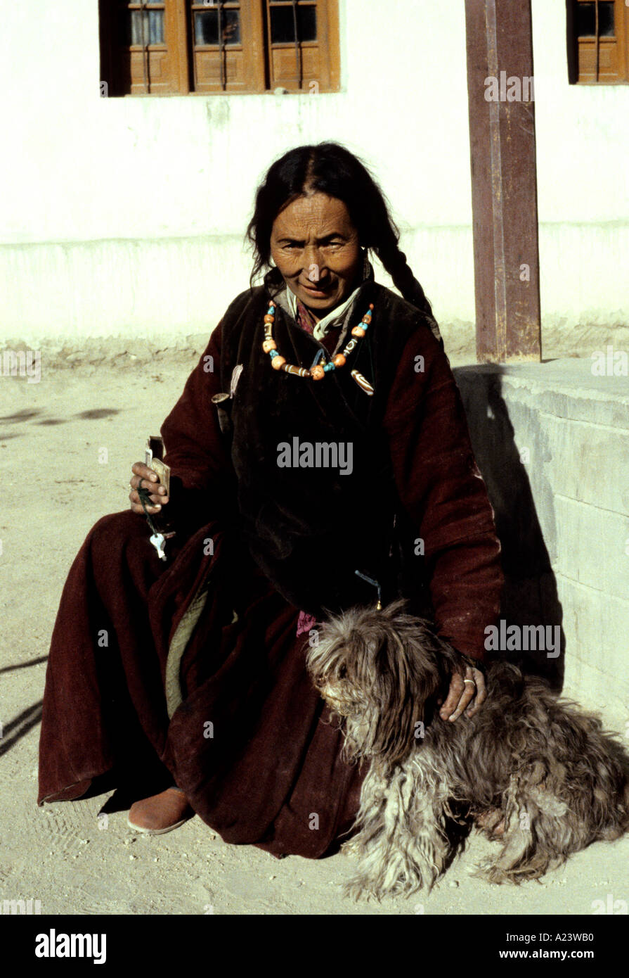 Propriétaire de l'hôtel Vue Palace à Leh, Ladakh est assis au soleil, porter des vêtements traditionnels et bijoux avec son animal de compagnie chien Lhassa Apso Banque D'Images