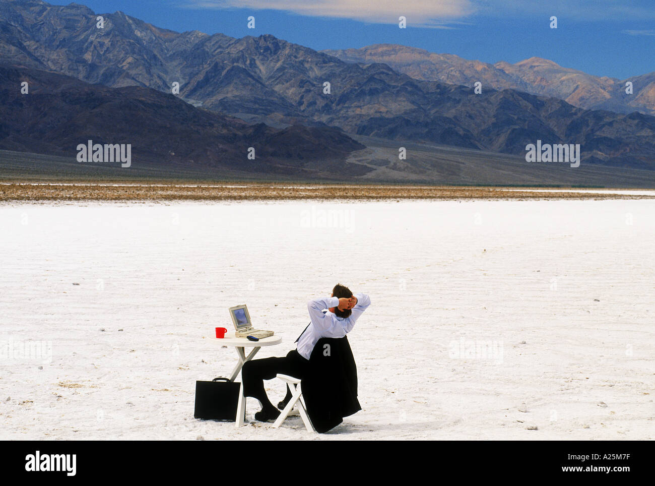 Businessman with laptop and cellphone sitting at table in California desert Banque D'Images