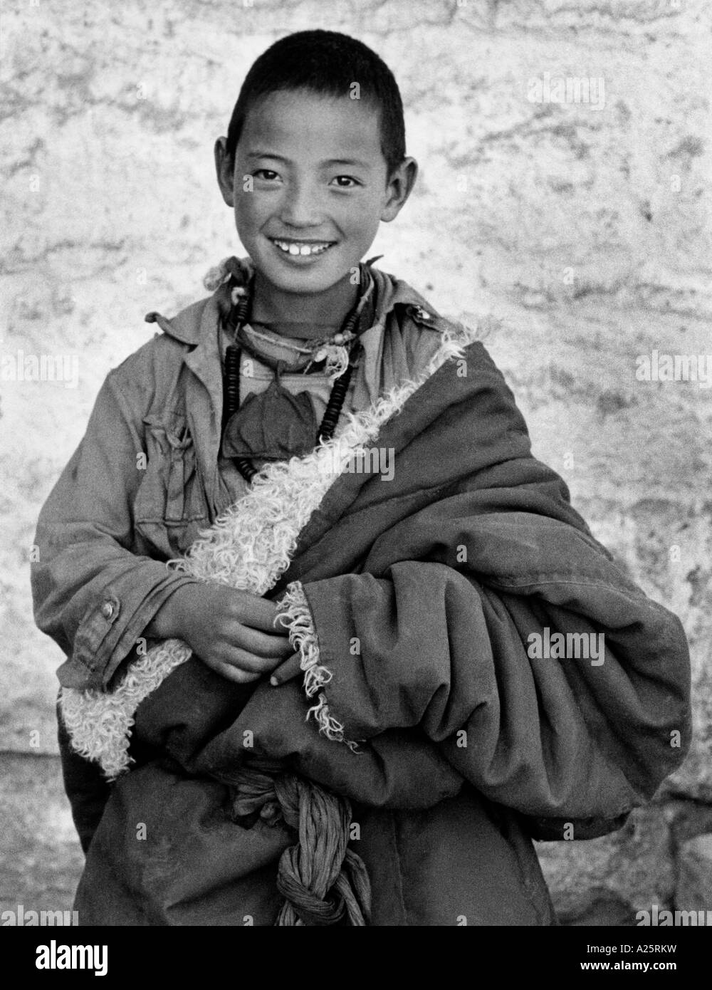 Un jeune moine tibétain sourit tout en portant sa peau de moutons chuba Lhassa au Tibet Banque D'Images