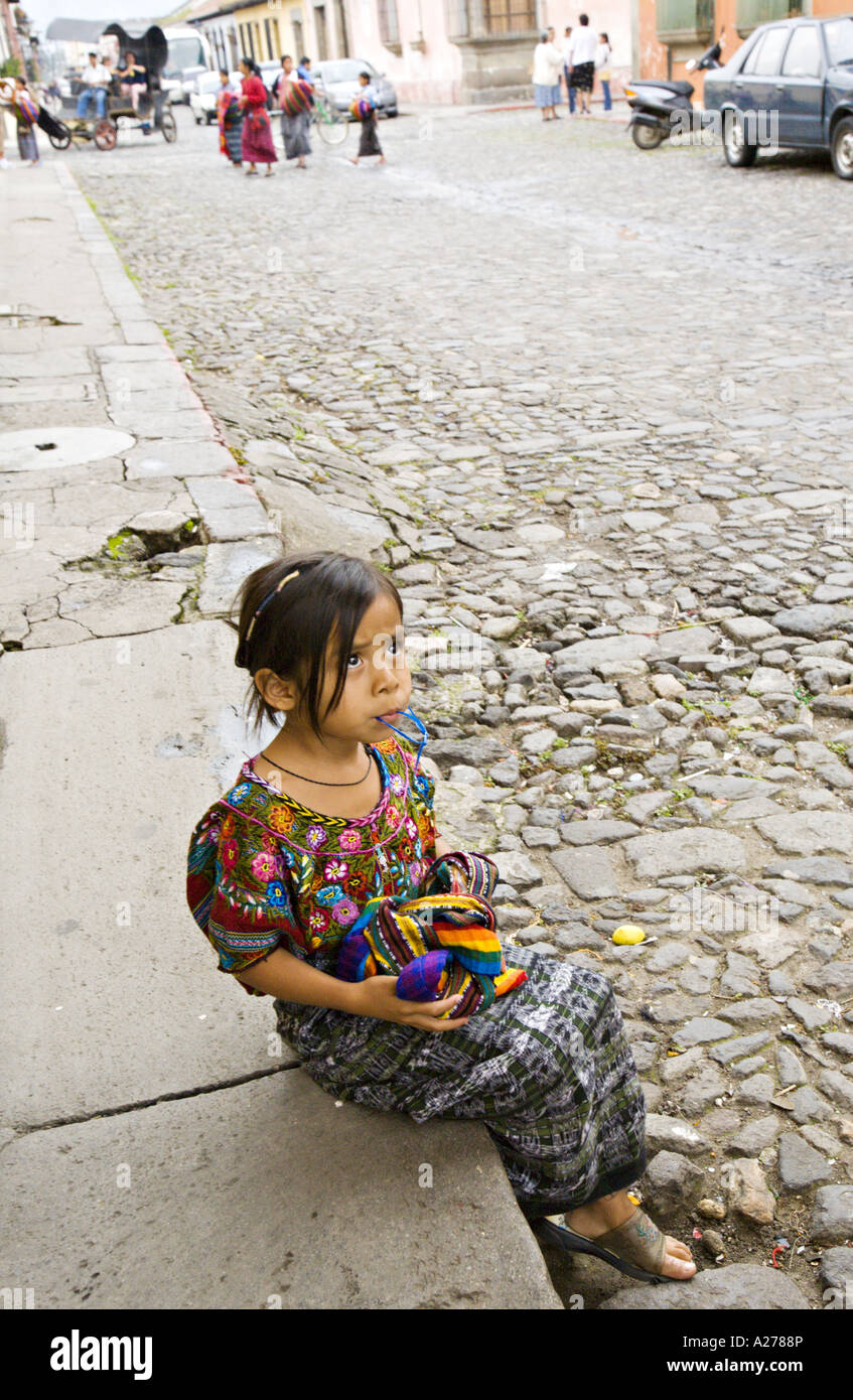 GUATEMALA ANTIGUA belle jeune fille assise Cakchiquel sur la bordure de couleur vive les textiles tissés à la vente Banque D'Images