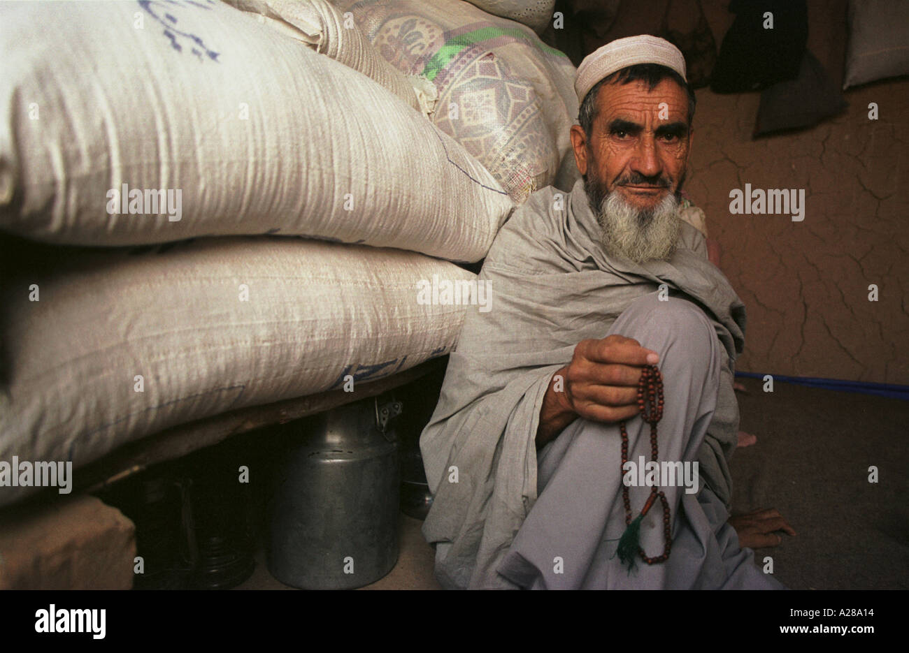 Un réfugié afghan Pakistan Peshawer se repose dans sa maison par une pile de stockage de sacs de farine pour nourrir sa famille Banque D'Images
