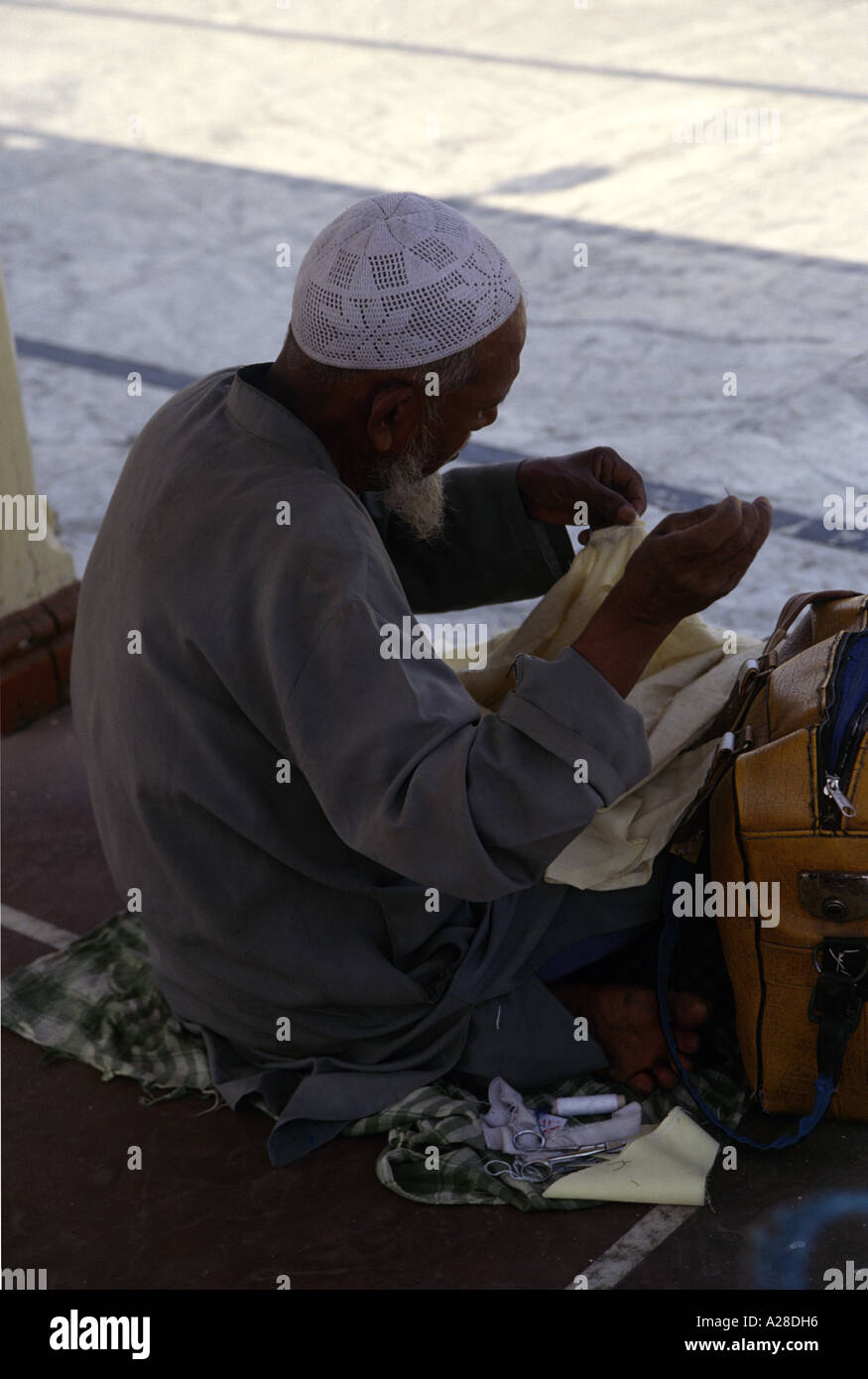 Un musulman vêtu du costume traditionnel chapeau de crâne est la couture en face de Jama ou Jami Masjid ; la photo est un quasi-silhouette Banque D'Images