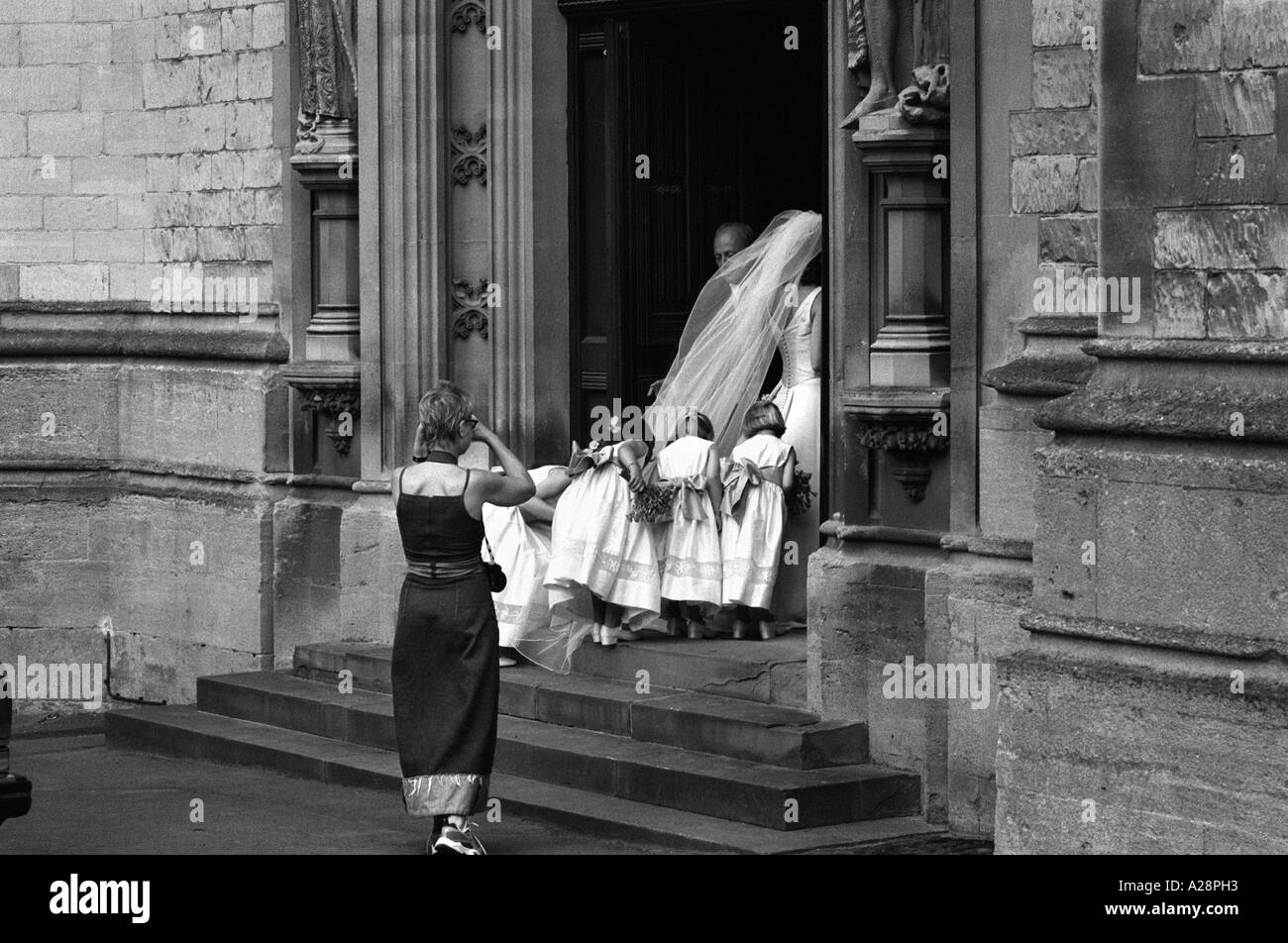 Une épouse qui va dans l'église pour son mariage, suivie de sa demoiselle d'être photographié Banque D'Images