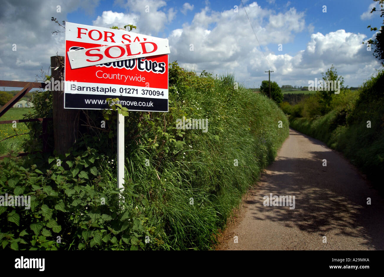 Un signe d'agents immobiliers dans un emplacement rural montrant vendus et à la vente sur un chemin de campagne Banque D'Images