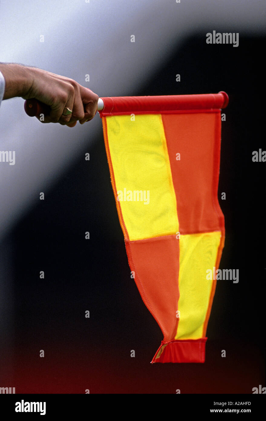 Les responsables du football main tenant un drapeau jaune et rouge indiquant une décision côté Banque D'Images