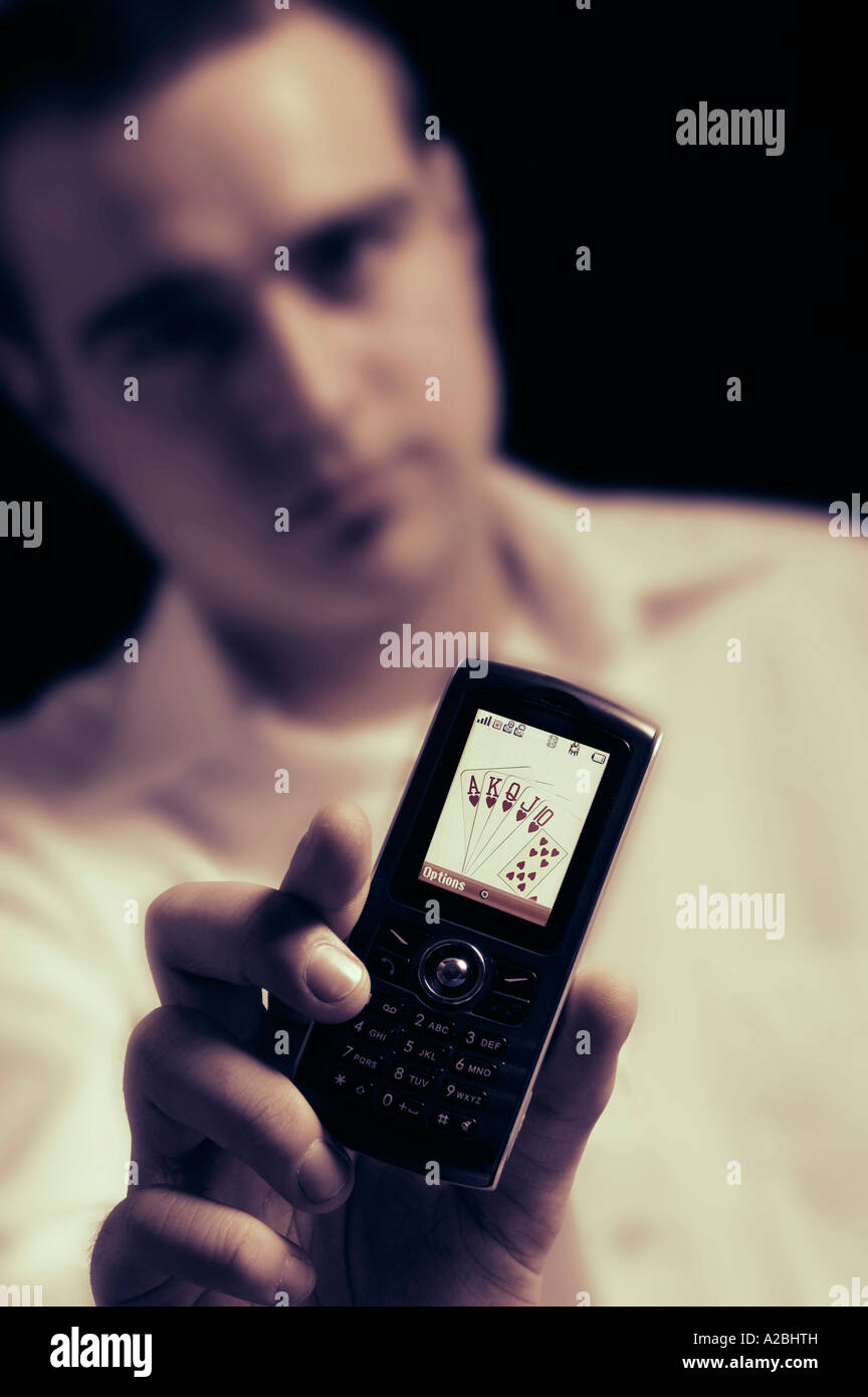 Jeune homme montrant royal flush sur téléphone mobile Banque D'Images