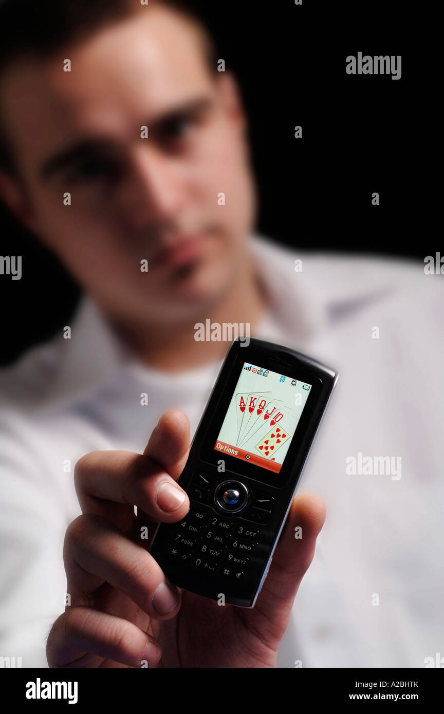 Jeune homme montrant royal flush sur téléphone mobile Banque D'Images