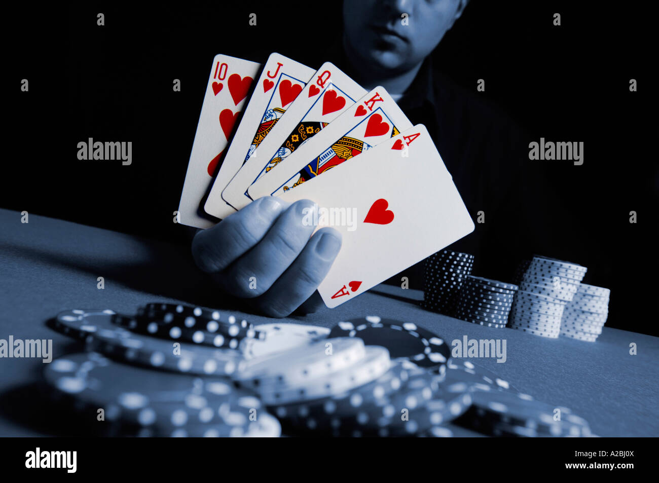 Jeune homme montrant Royal Flush at poker table Banque D'Images
