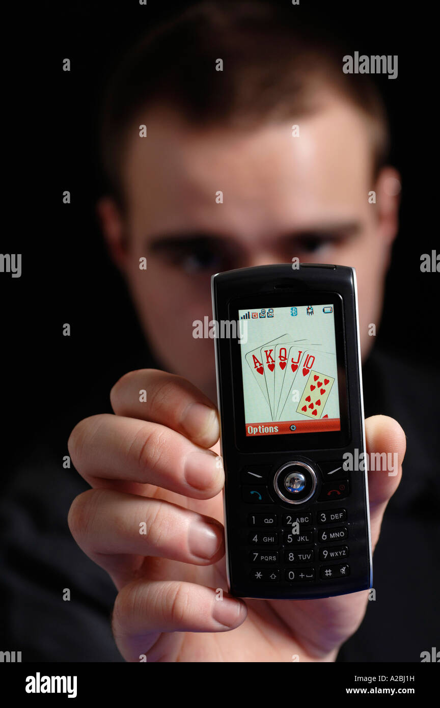 Jeune homme montrant Royal Flush sur téléphone mobile Banque D'Images