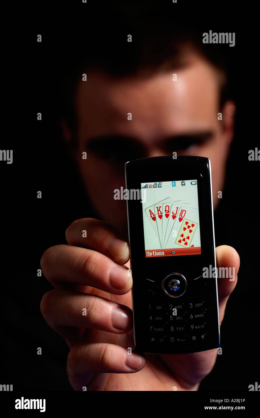Jeune homme montrant Royal Flush sur téléphone mobile Banque D'Images
