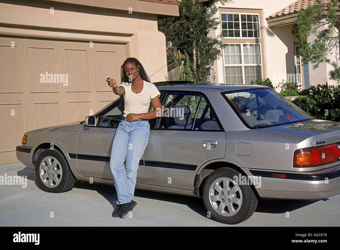 Young African American female teenager standing en voiture dans l'entrée de jour en prouholding Myrleen touches POV MR © Pearson Banque D'Images