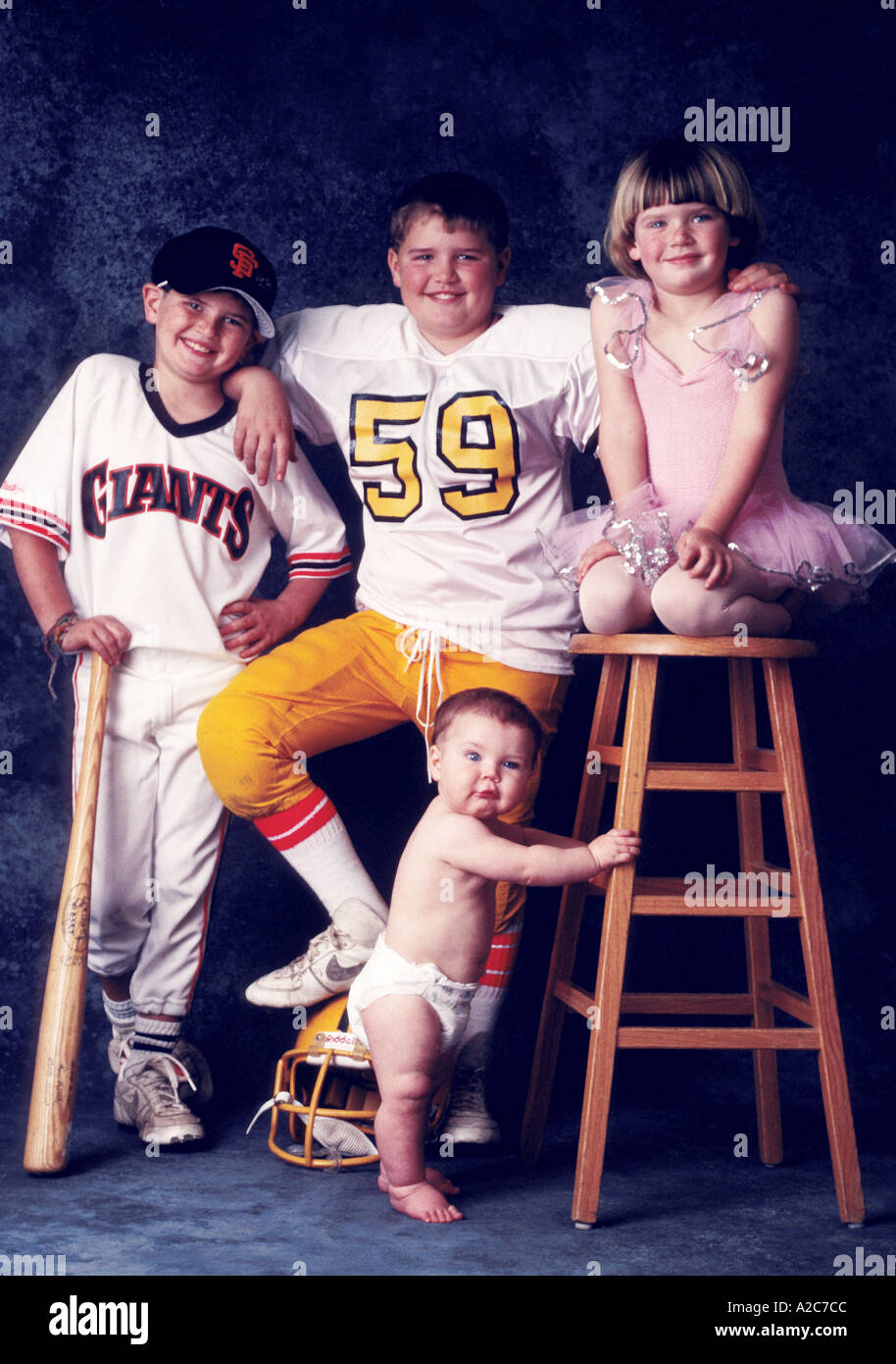 Portrait de 3 frères et une soeur Elles se composent d'une ballerine un joueur de baseball joueur de football et un bébé Banque D'Images