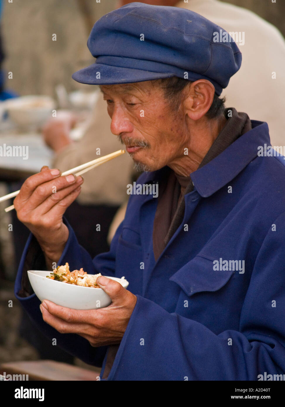 Vieil homme en costume mao Chine Dali eating noodles Banque D'Images