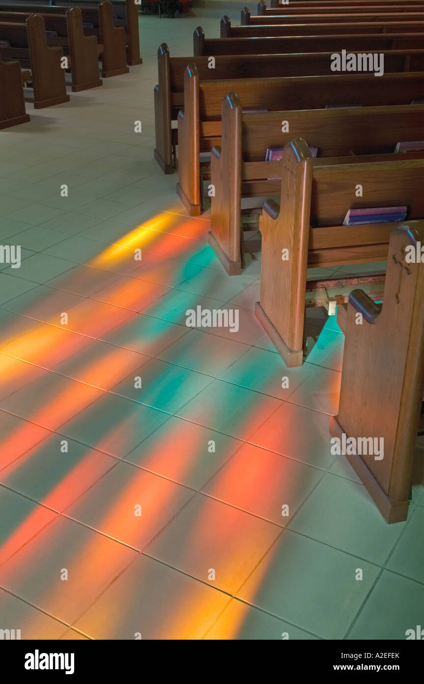 Bancs d'église avec vitrail de lumière qui brille sur le sol faisant un motif coloré à l'Église catholique romaine, USA Banque D'Images