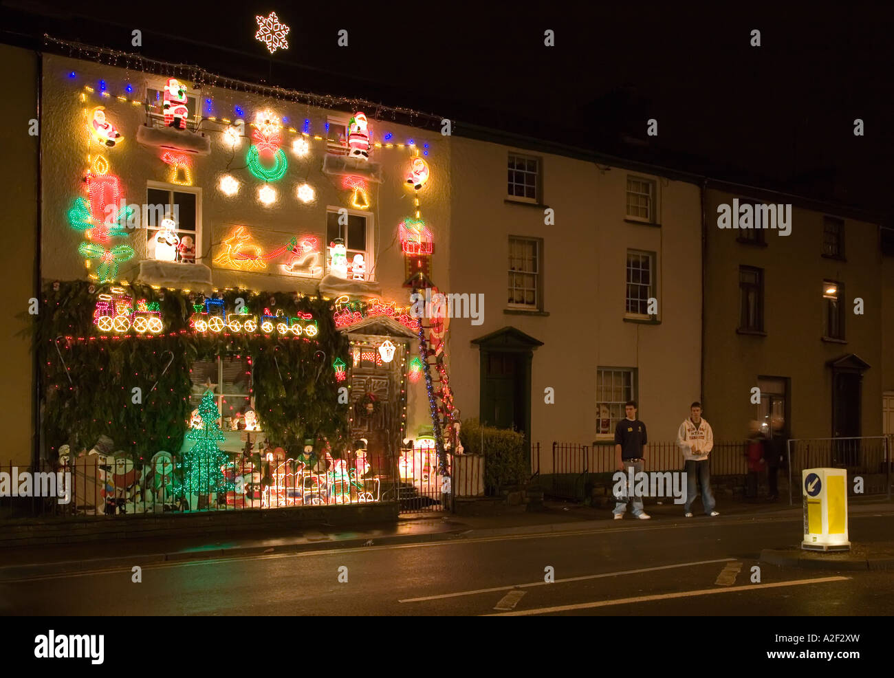 Les gens sur le pavé à l'extérieur des décorations de Noël sur la maison qui sert à recueillir pour la charité Abergavenny Wales UK Banque D'Images