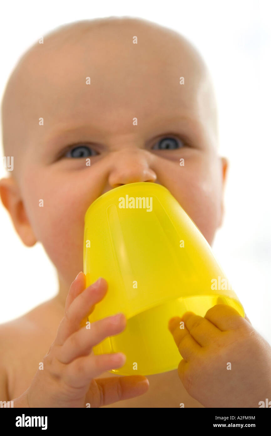 Bébé garçon (6-12 mois) holding cup jaune, close-up Banque D'Images