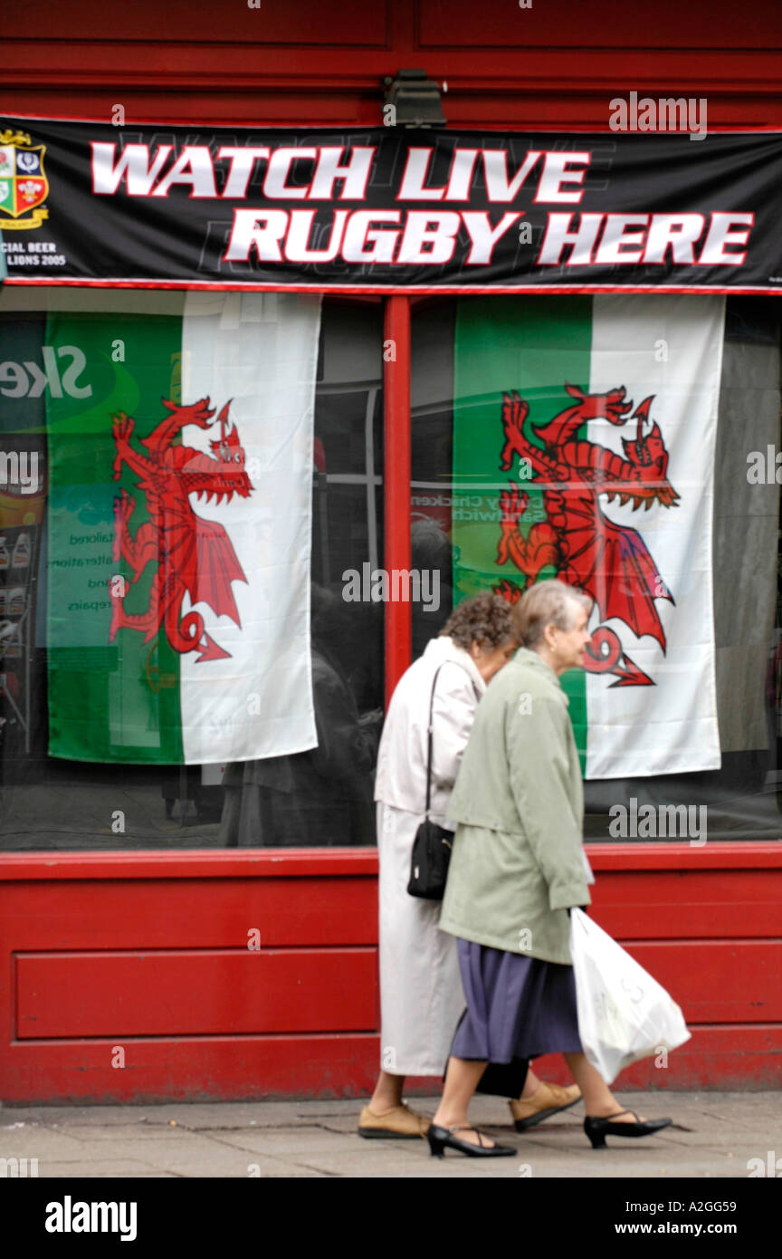 Publicité Pub rugby live dragon rouge drapeaux dans la fenêtre et deux cadres chers passé à pied dans le centre-ville de Cardiff South Wales UK Banque D'Images