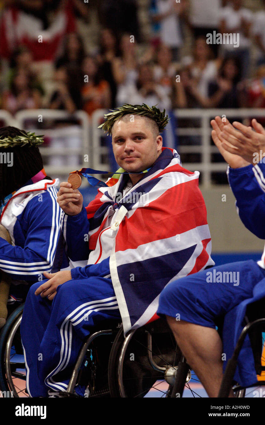Drapés dans l'Union Jack, Jon Pollock de GBR montre sa médaille de bronze pour la mens open basket-ball Jeux paralympiques d'Athènes Banque D'Images