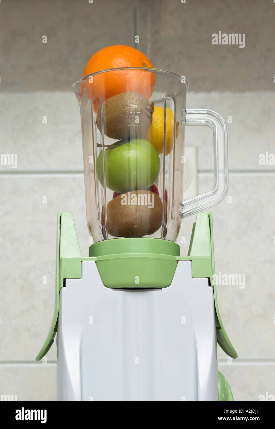 Le mélangeur rempli de divers fruits pommes kiwies orange citron Banque D'Images