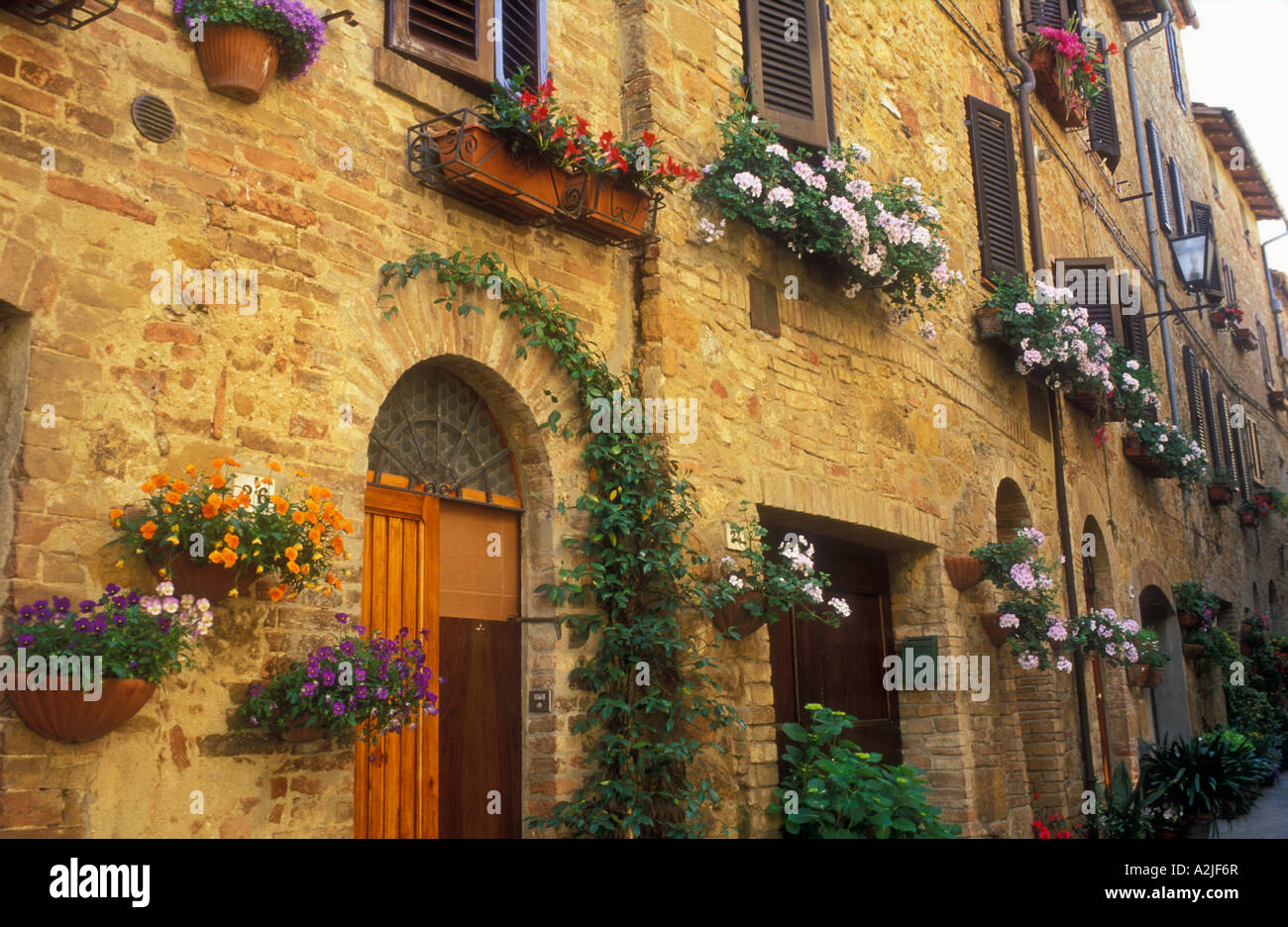 Italie Pienza toscane de pots de fleurs et suspendu le long d'un mur avec des portes Banque D'Images