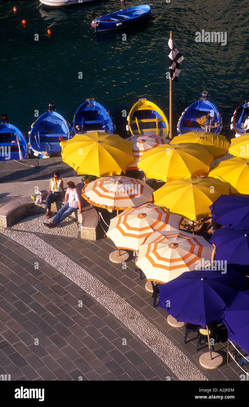 Italie Cinque Terre Ligurie Vernazza parasols colorés de bateaux de pêche et un couple assis Banque D'Images