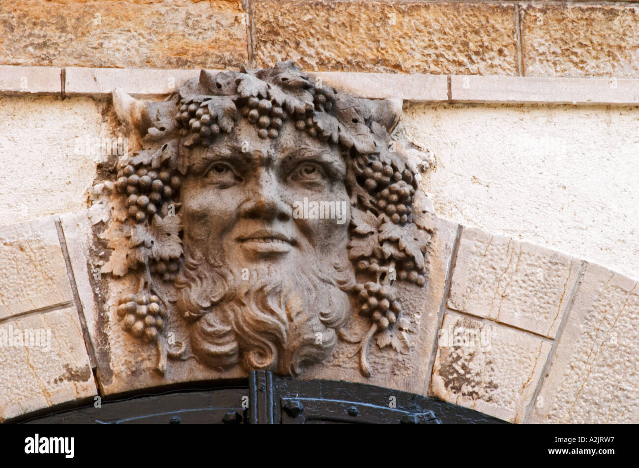Une sculpture de baccus bacchus baccus avec barbe et de grappes de raisin et feuilles de vigne dans les cheveux comme la clé de voûte d'une pierre tombale Banque D'Images
