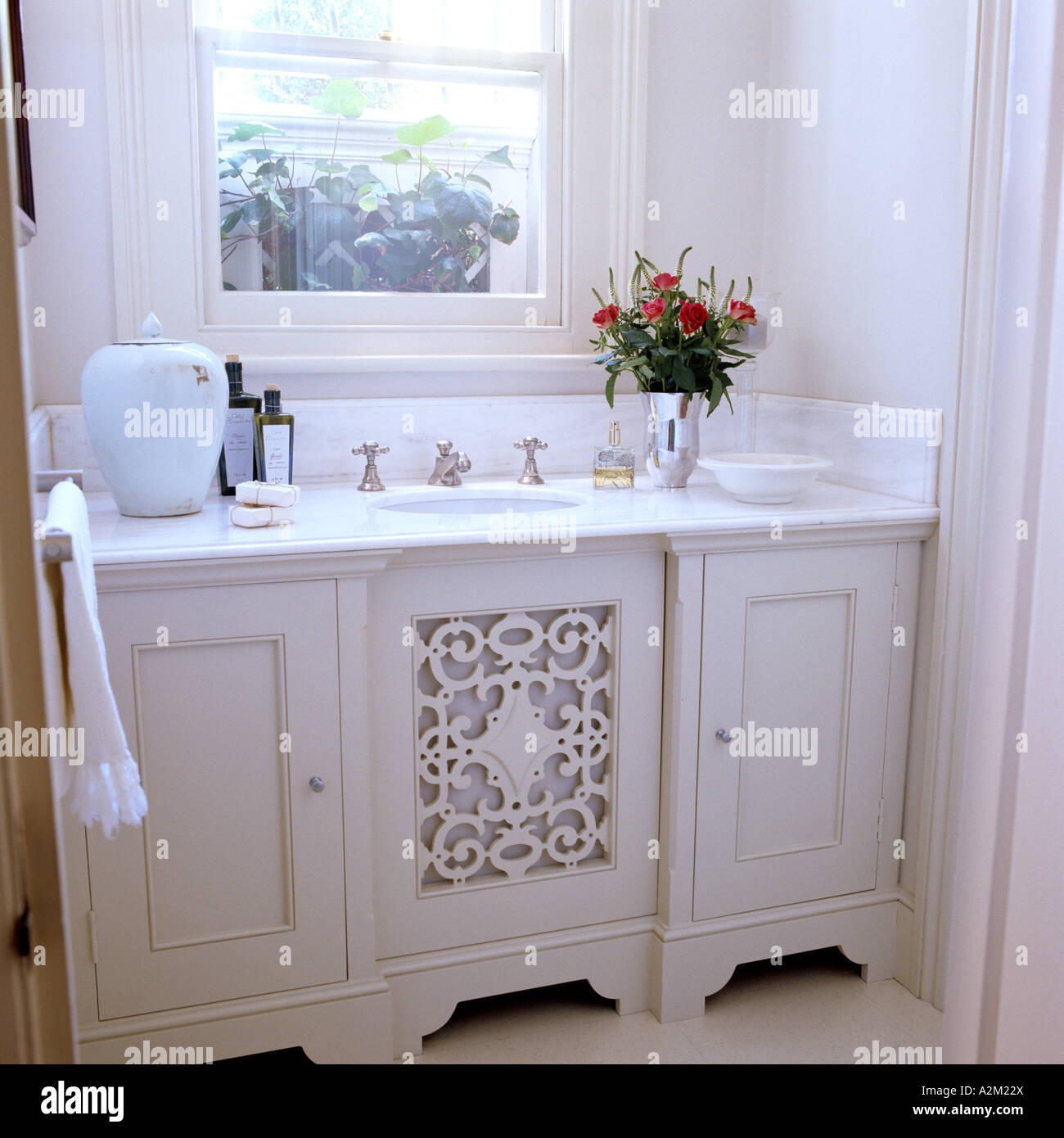 Lavabo avec vase et arrangement floral sous Fenêtre. Banque D'Images