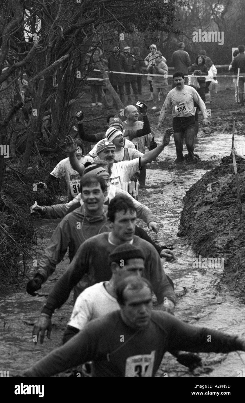 Les concurrents de patauger dans la boue froide en cours de Course Tough Guy à Tettenhall, West Midlands, England, UK Banque D'Images