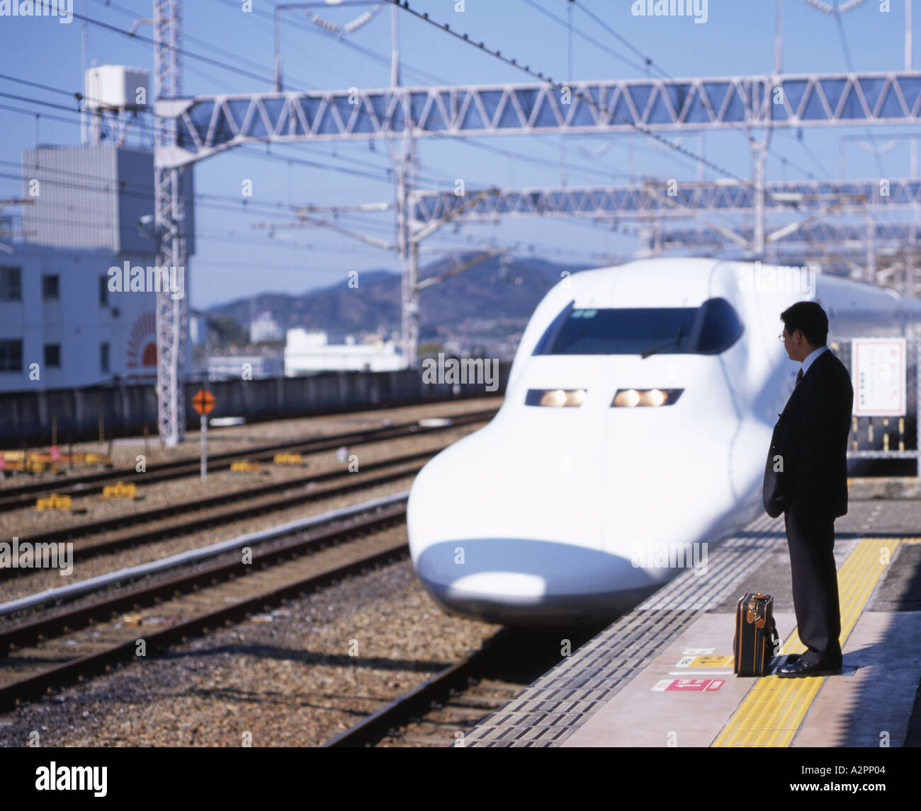 Businessman se dresse sur le platfrom attendant l'arrivée du train à grande vitesse Shinkansen Banque D'Images
