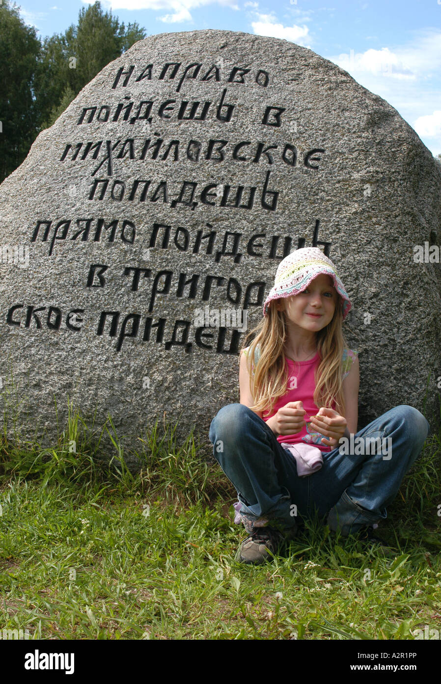 Assis à côté du jeune visiteur pierre énorme montrant les directions autour de la colline de Pouchkine réserver dans la région de Pskov, Russie Banque D'Images