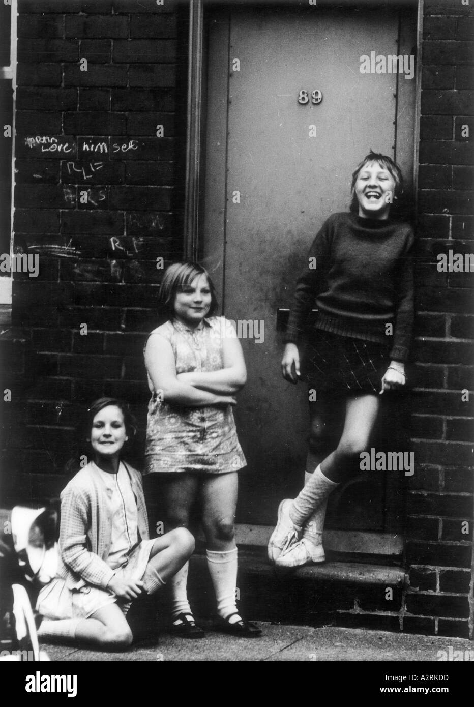 Photographie en noir et blanc d'enfants se tenant sur le pas de leur porte Banque D'Images