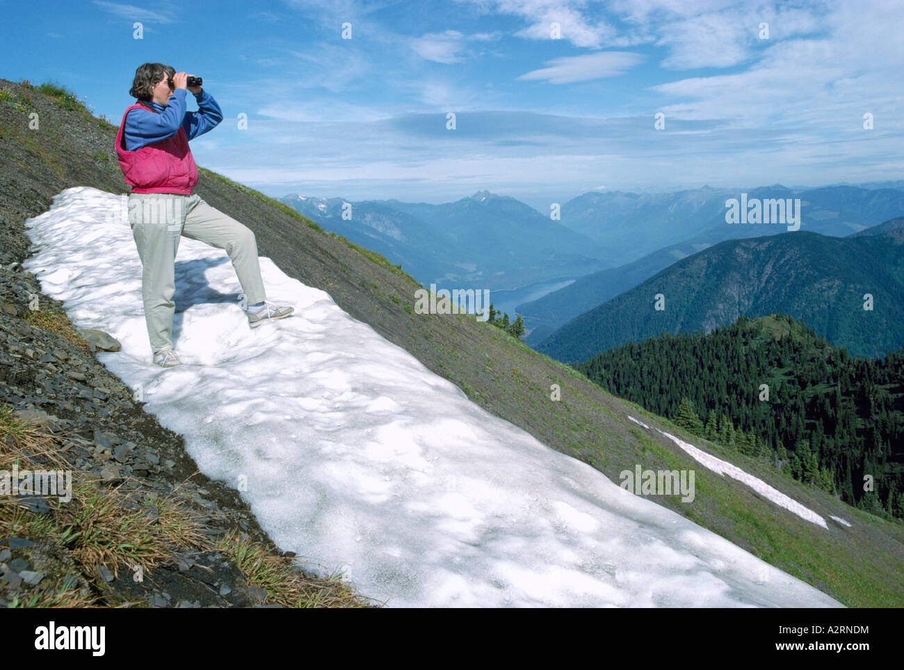 Femme regardant à travers des jumelles à Selkirk Mountains de l'Idaho Peak, BC, en Colombie-Britannique, Canada - Randonnées dans la région de Kootenay Banque D'Images