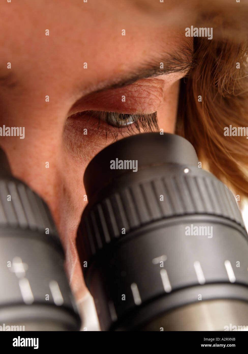 Femme regardant dans l'oculaire du microscope close up Banque D'Images