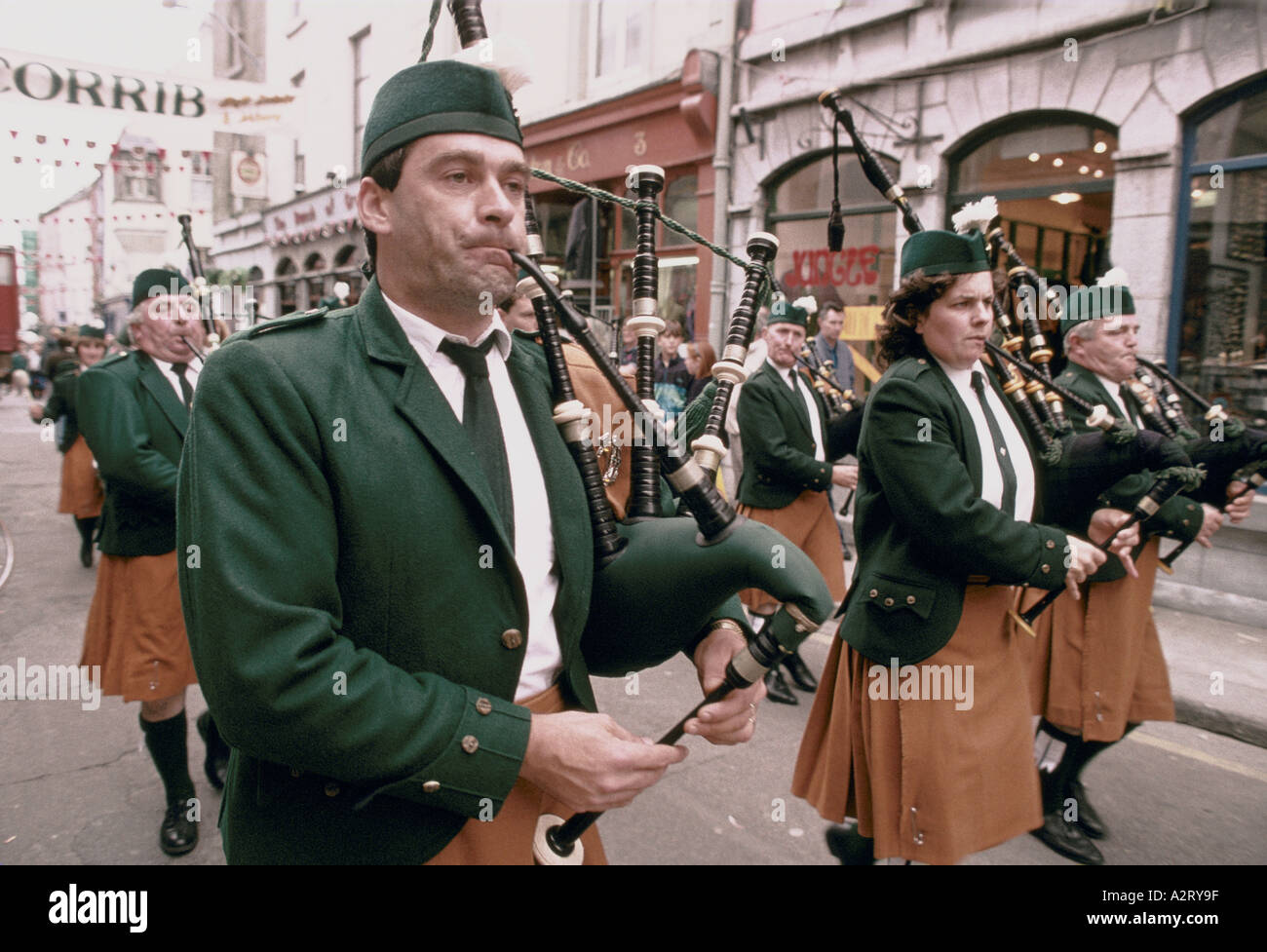Hommes femmes en uniforme en marchant le long de la bande de cornemuse pendant rue Irlande Galway oyster festival guinness Banque D'Images