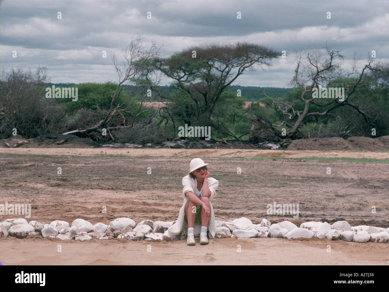 Woman wearing white pith helmet assis sur un chemin dans une réserve de chasse de l'Afrique du Sud Banque D'Images