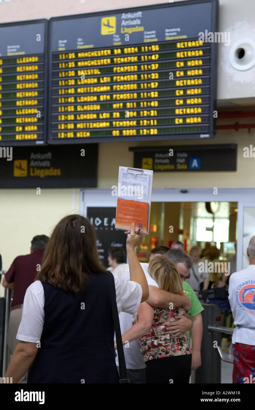 Guide féminin espagnol attend devant le terminal des arrivées message board avec liste des passagers du Reina Sofia sur TFS Banque D'Images
