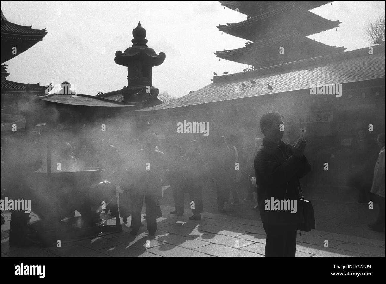 Prie l'homme tenue à l'encens de Senso Ji dans le quartier d'Asakusa, Tokyo, Japon, Asie Banque D'Images