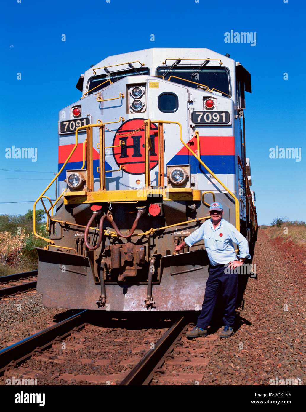 L'ouest de l'Australie. Le pilote du moteur de train de minerai de fer de l'homme posant devant de la locomotive sur la voie de l'outback. Banque D'Images