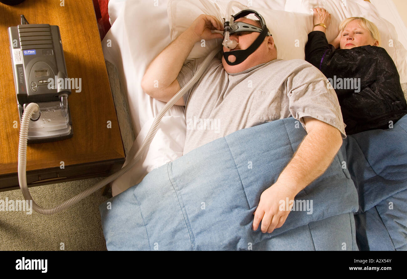L'homme et la femme au lit en train de dormir. L'homme porte un appareil CPAP - Pression Positive Continue Banque D'Images