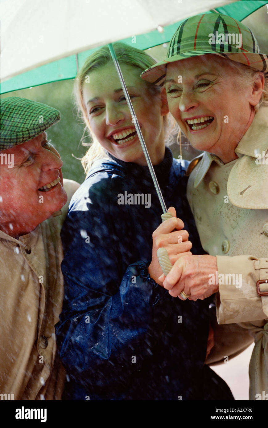 Des profils famille en plein air à l'abri de la pluie sous un parapluie. Banque D'Images