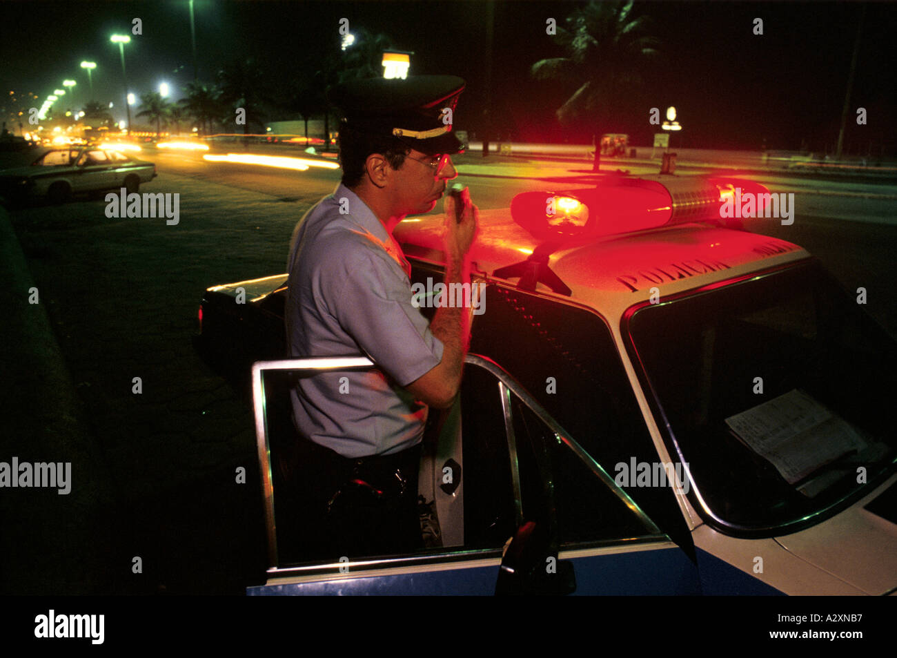 Officier de police debout en voiture de patrouille la nuit sur Copacabana, Rio de Janeiro, 1991. Banque D'Images