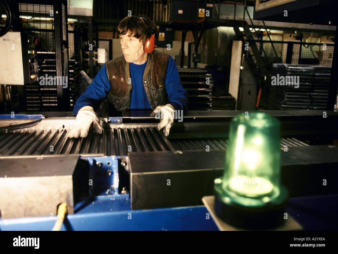 Homme portant un protège-oreilles sur une chaîne de montage Banque D'Images
