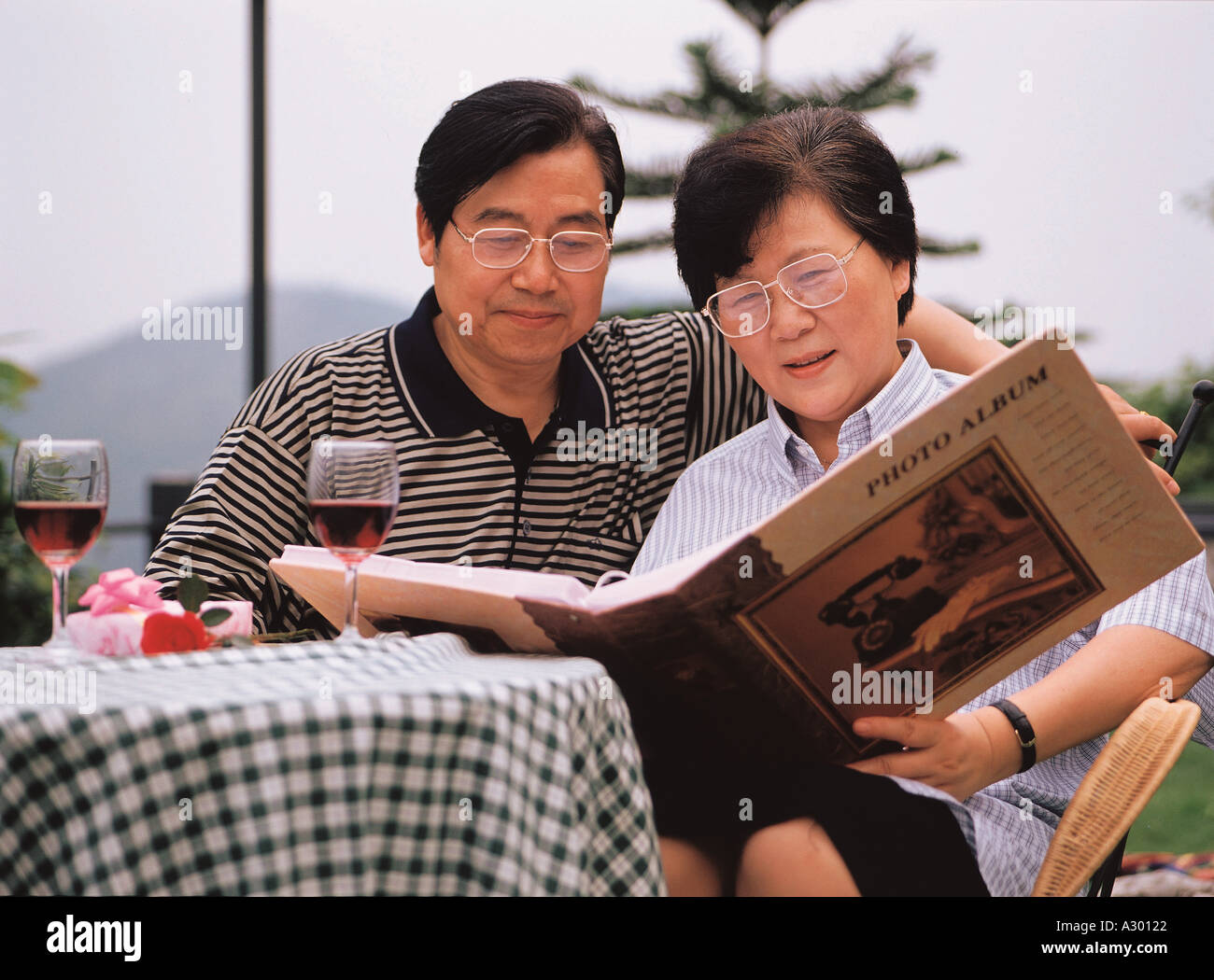 Couple chinois assis sur un banc en regardant un album photo Banque D'Images